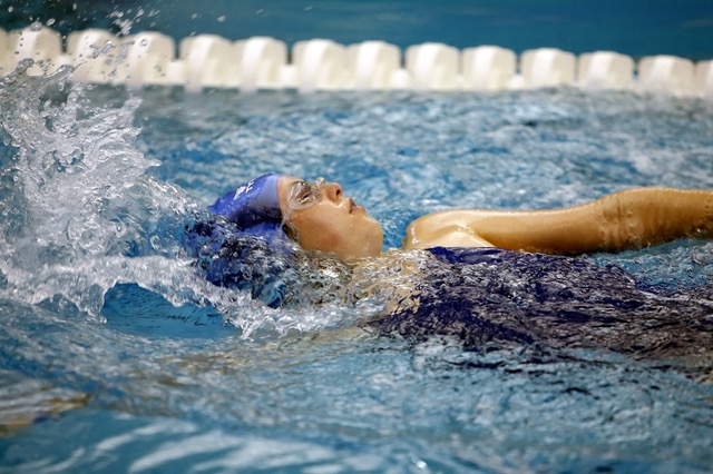 woman swimming backstroke in an indoor pool