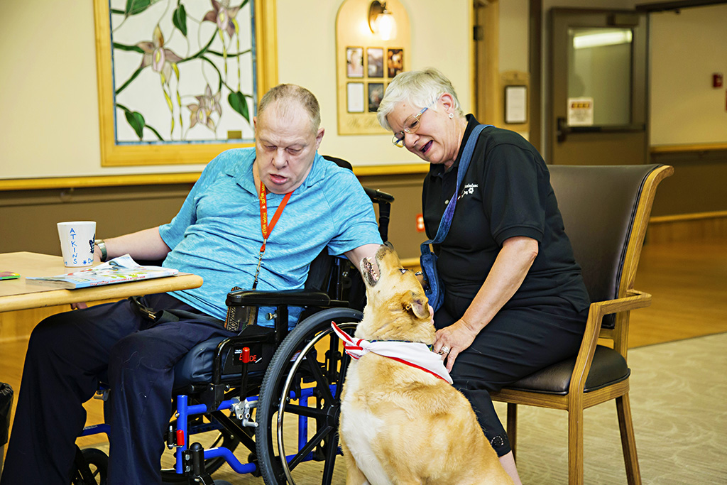 Male resident and volunteer enjoying pet therapy program