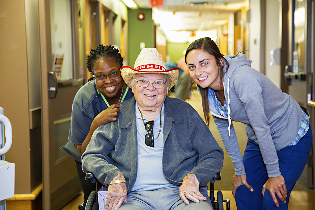 Male resident in a wheelchair in between to staff members