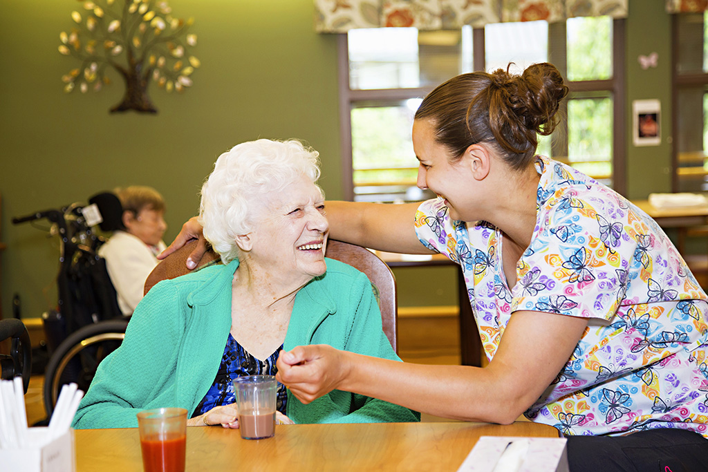 Staff member and resident laughing together during meal service