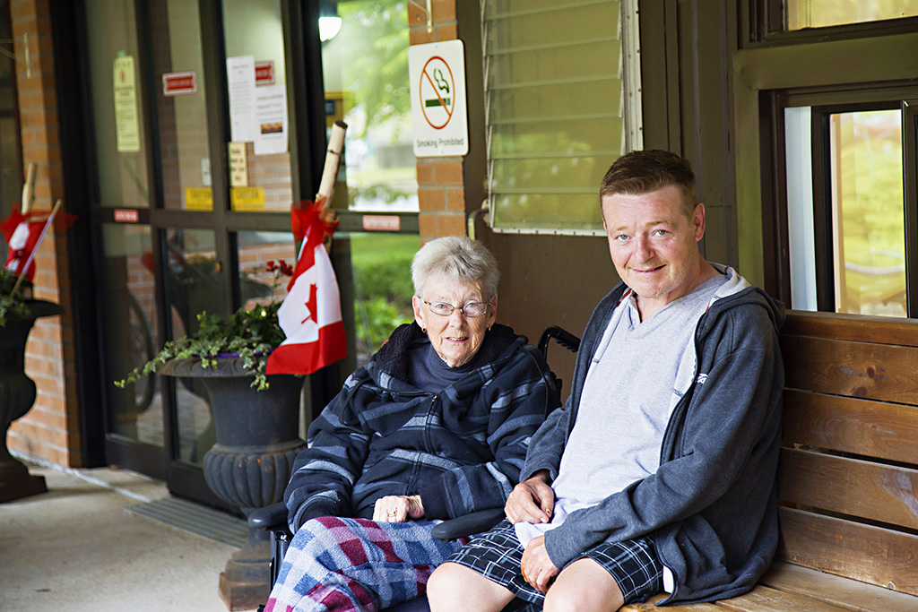 Male and Female resident sitting outside the front entrance to Spruce Lodge 