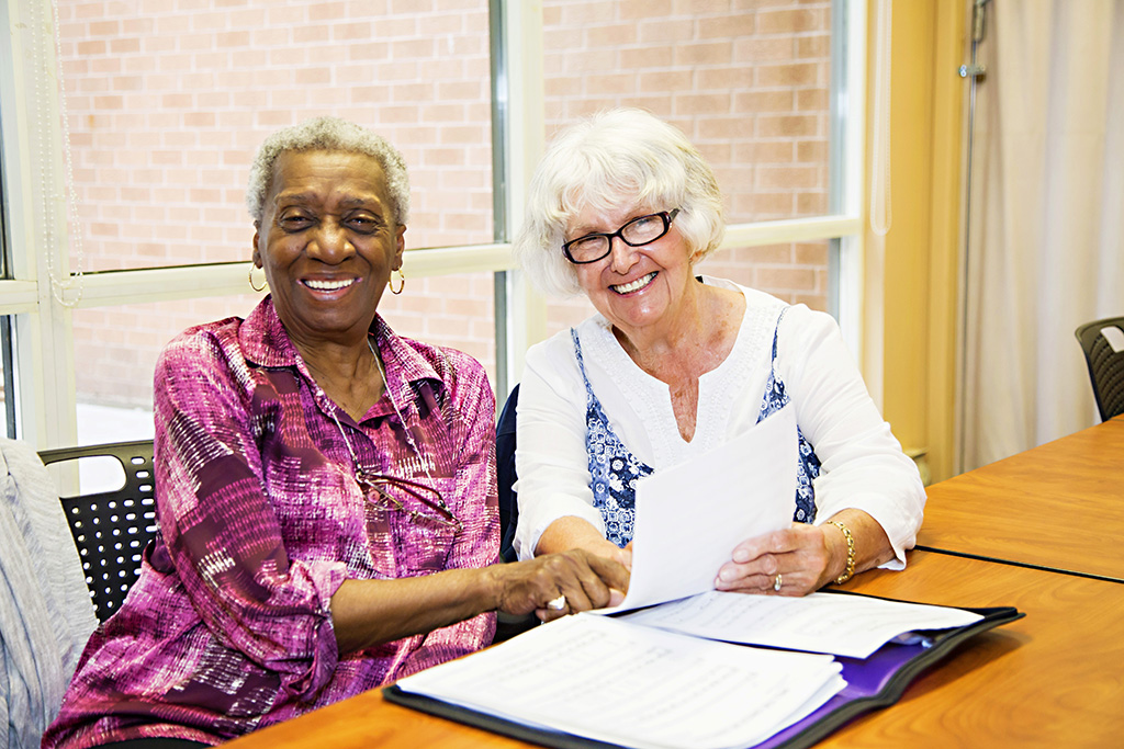 Two female residents laughing over paperwork together