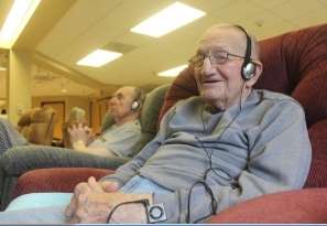 Senior Gentleman wearing headphones listening to music and smiling while relaxing in a recliner