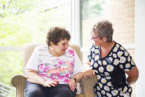 Resident and Staff member in scrubs talking 