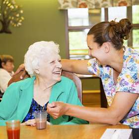Female resident and PSW laughing in the dining room together