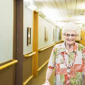 Female resident walking in hallway with a big smile
